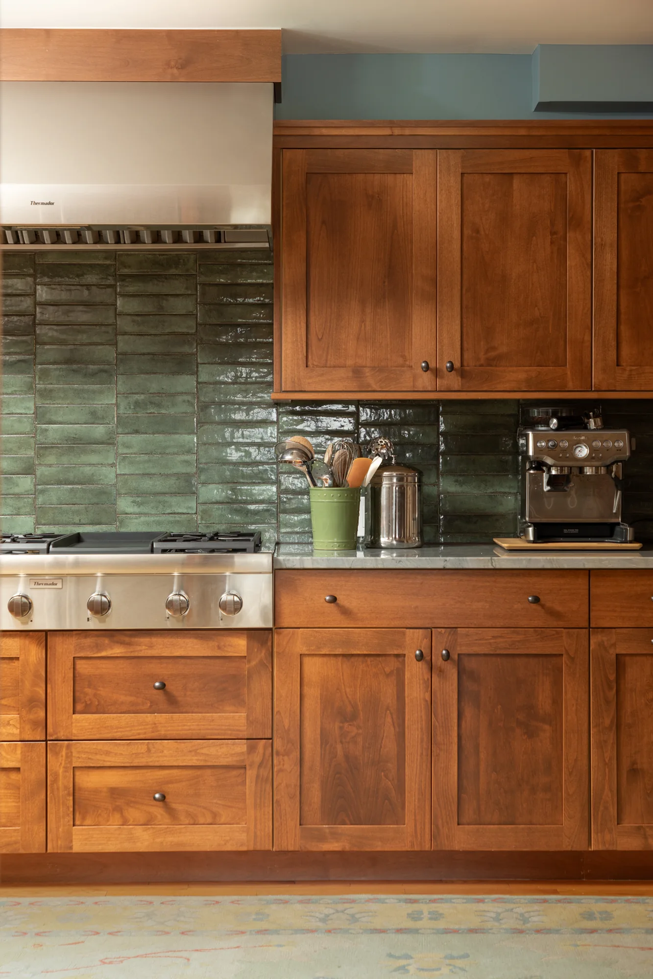 Cherry cabinetry and glazed green tile in a kitchen remodeled by ABD